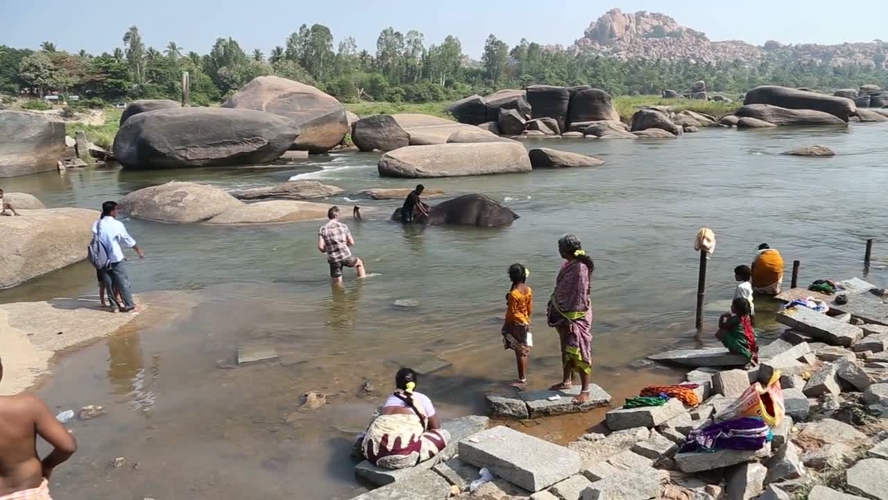 Elephant Lakshmi lying in the river and people at the riverbank