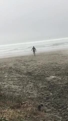 Guy in wetsuit on the beach does stretches