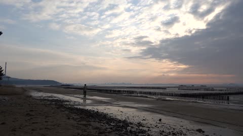 A man walking on a washed-out beach