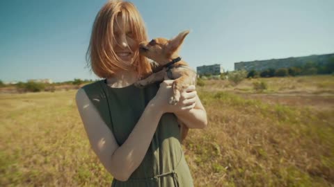 Beautiful young hipster woman walking with funny chihuahua dog outdoors on field