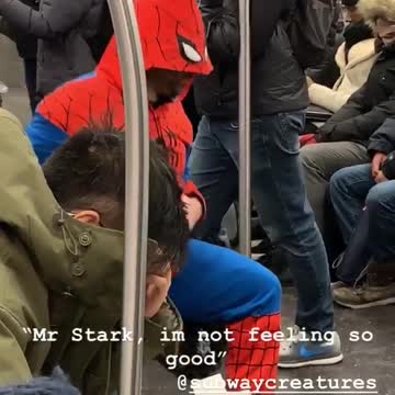Guy in spiderman suit stretches legs on subway train