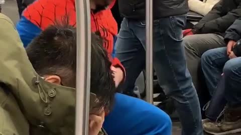 Guy in spiderman suit stretches legs on subway train