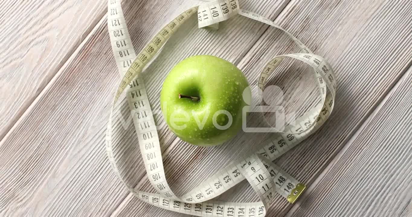 Green apple and measuring tape on table