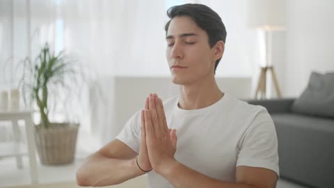 Closeup of man in Namaste yoga pose in living room