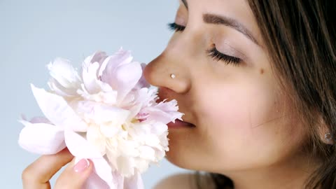 Young woman smelling a white flower