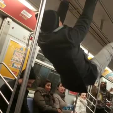 Drunk guy on subway holds onto ceiling hand rail and humps the roof