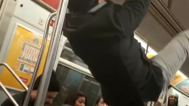 Drunk guy on subway holds onto ceiling hand rail and humps the roof