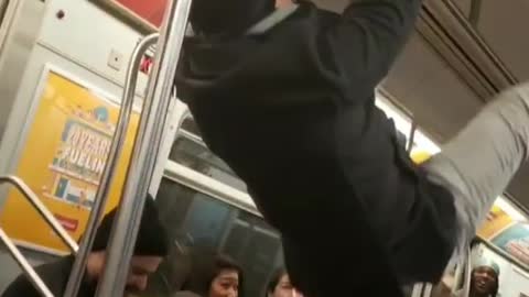 Drunk guy on subway holds onto ceiling hand rail and humps the roof