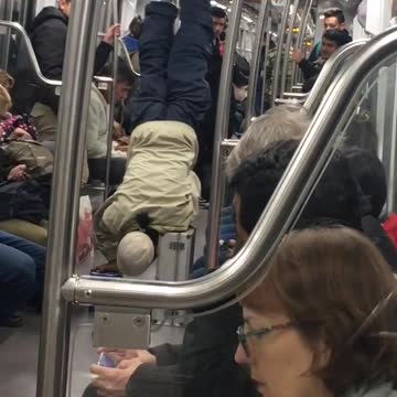 Older man in hate does hand stand on train