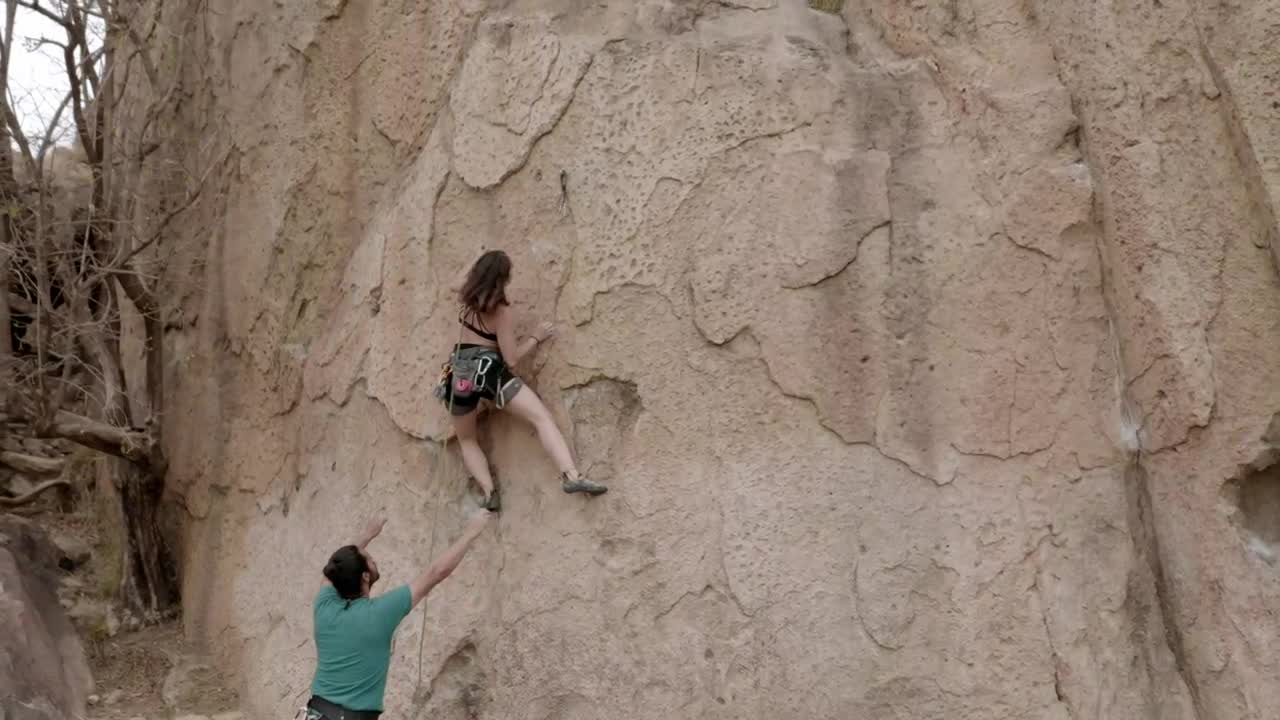 Man and woman climbers climbing a big rock