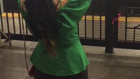 Girl in green shirt dancing in subway station