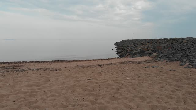 Quadrocopter flies over the beach towards the lake