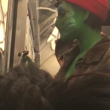Woman with reptile make up on her face takes a selfie on subway train