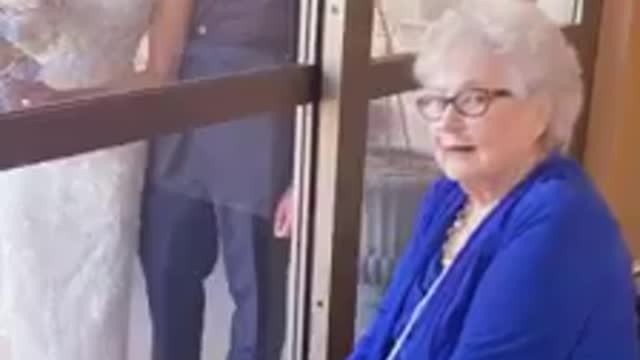 Bride visits her grandmother through glass on wedding day