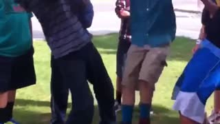 Kids flip a boy in blue he face plants on grass