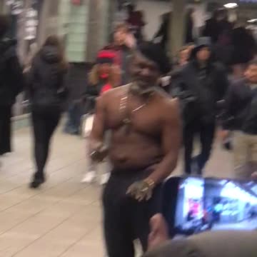 Shirtless man dances to drum beat at subway station