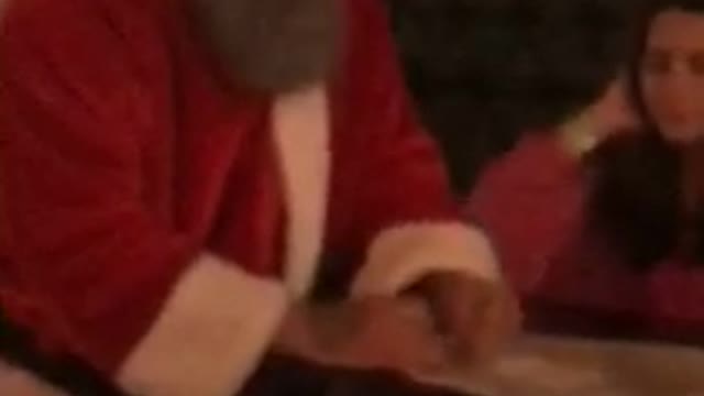 Girl sleeping at table next to guy dressed up as santa