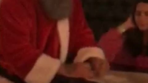 Girl sleeping at table next to guy dressed up as santa