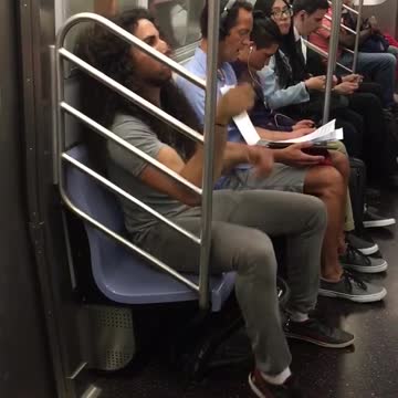 Man with long curly hair bobbing head on train