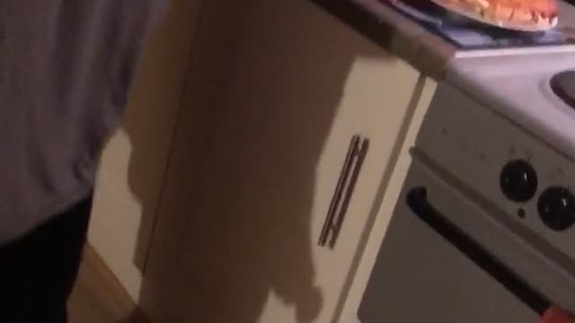 Guy in gray trying to cut pizza drops it