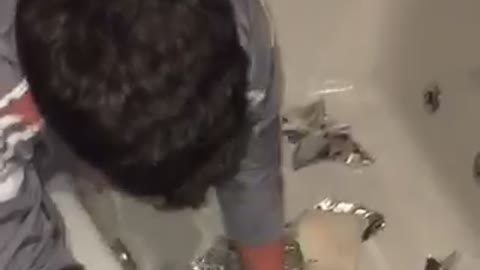 Guy reaching into bathtub full of tin foil