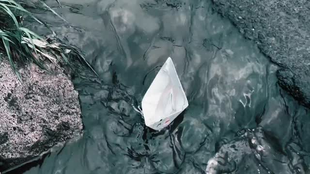 a-paper-boat-floating-over-a-roadside-water-canal