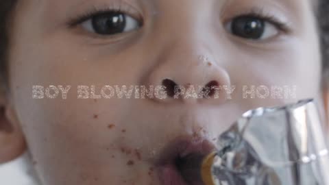 A Boy Blowing a Party Horn