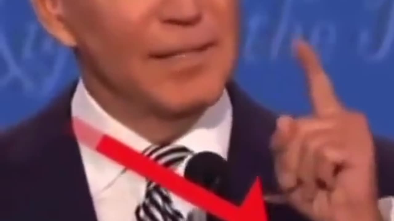 Biden has some sort of a hand microphone or an implant that retracts, seen at a conference