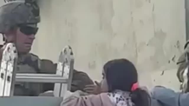 Us soldier lift little girl over the wall in Kabul airport