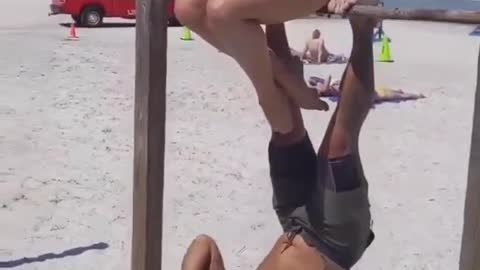 Guy Workouts At Beach While Hanging Upside Down On a Rod