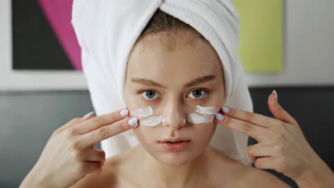 A Woman Applying Facial Cream On Her Face