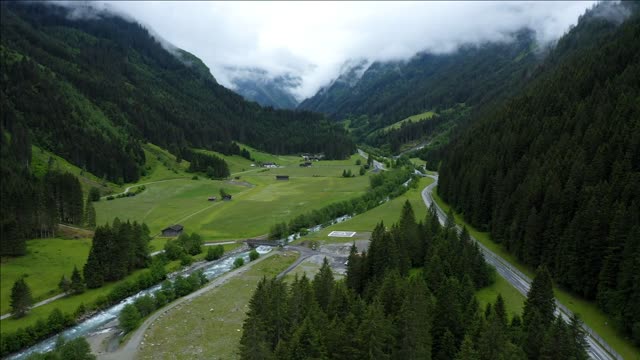 aerial footage apline valley with river road and pine tree forest tirol austria