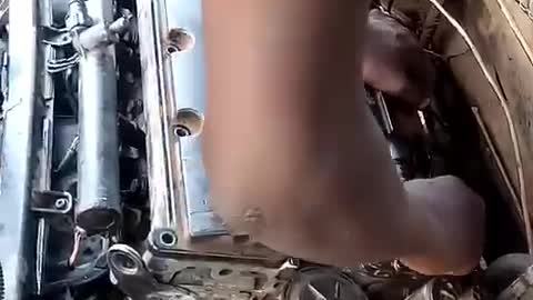 A 12 years old Boy fixing a full engine Car without been supervised