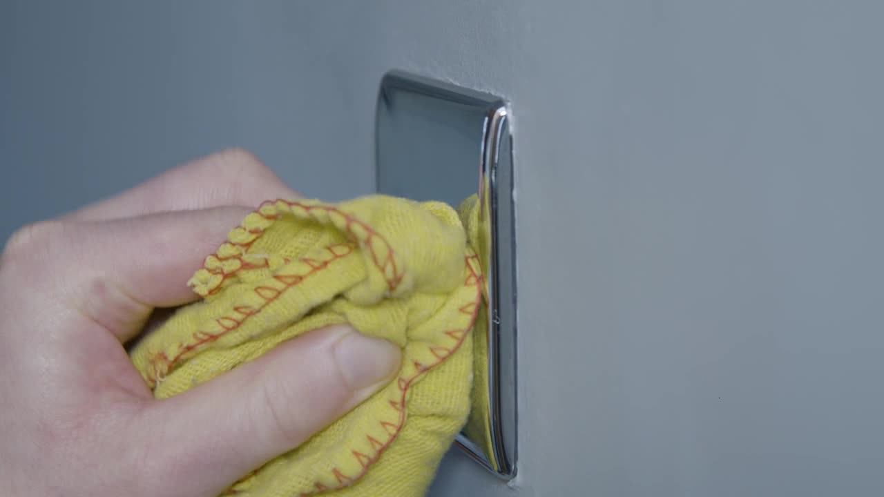 Sliding Close Up Shot of Male Hand Cleaning a Light Switch On Wall