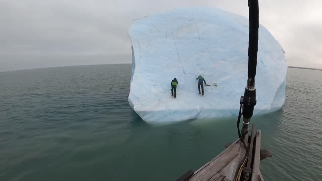 people climb an iceberg then it flips over