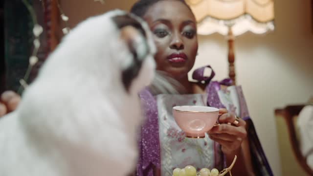 A Woman Petting A Cat While Having Tea