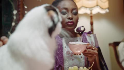 A Woman Petting A Cat While Having Tea