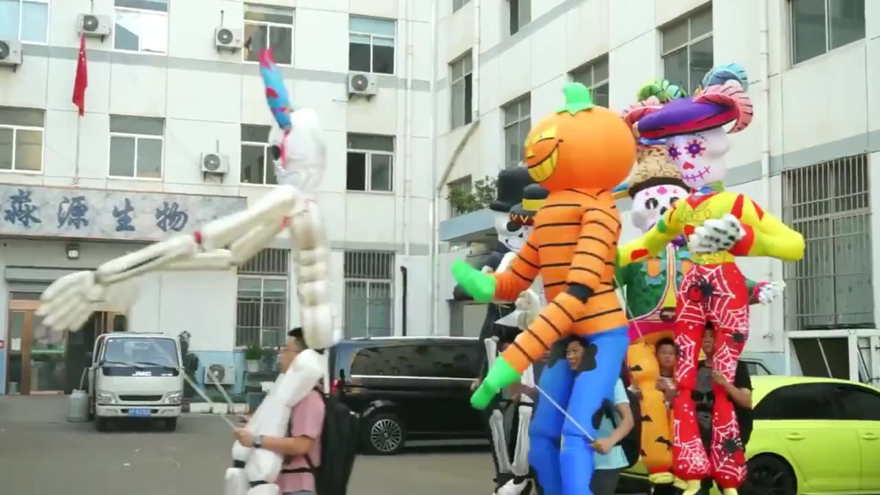 People Walk Around With Inflatable Halloween Puppets Overhead.