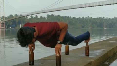 Guy Does Push-Ups by Balancing on Four Glass Bottles