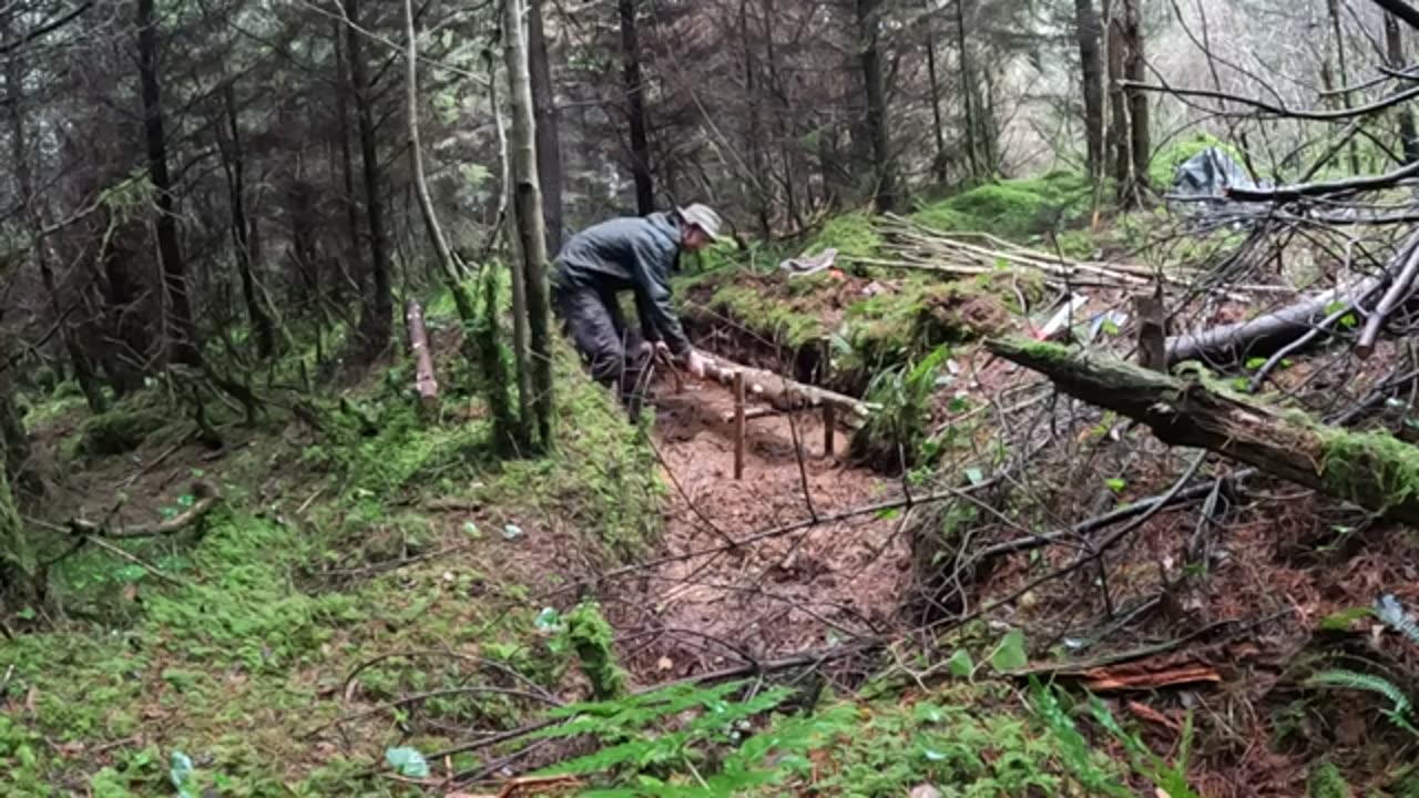 Building a stealth bushcraft survival shelter in the woods- Part 2 - raised bed in the mud!