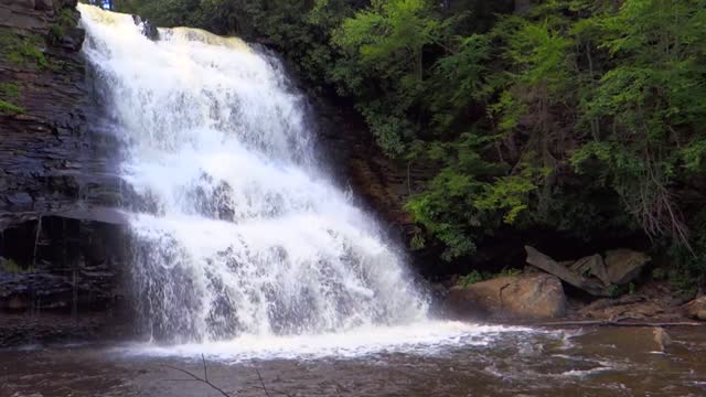 Beautiful rushing waterfall and small river amongst nature