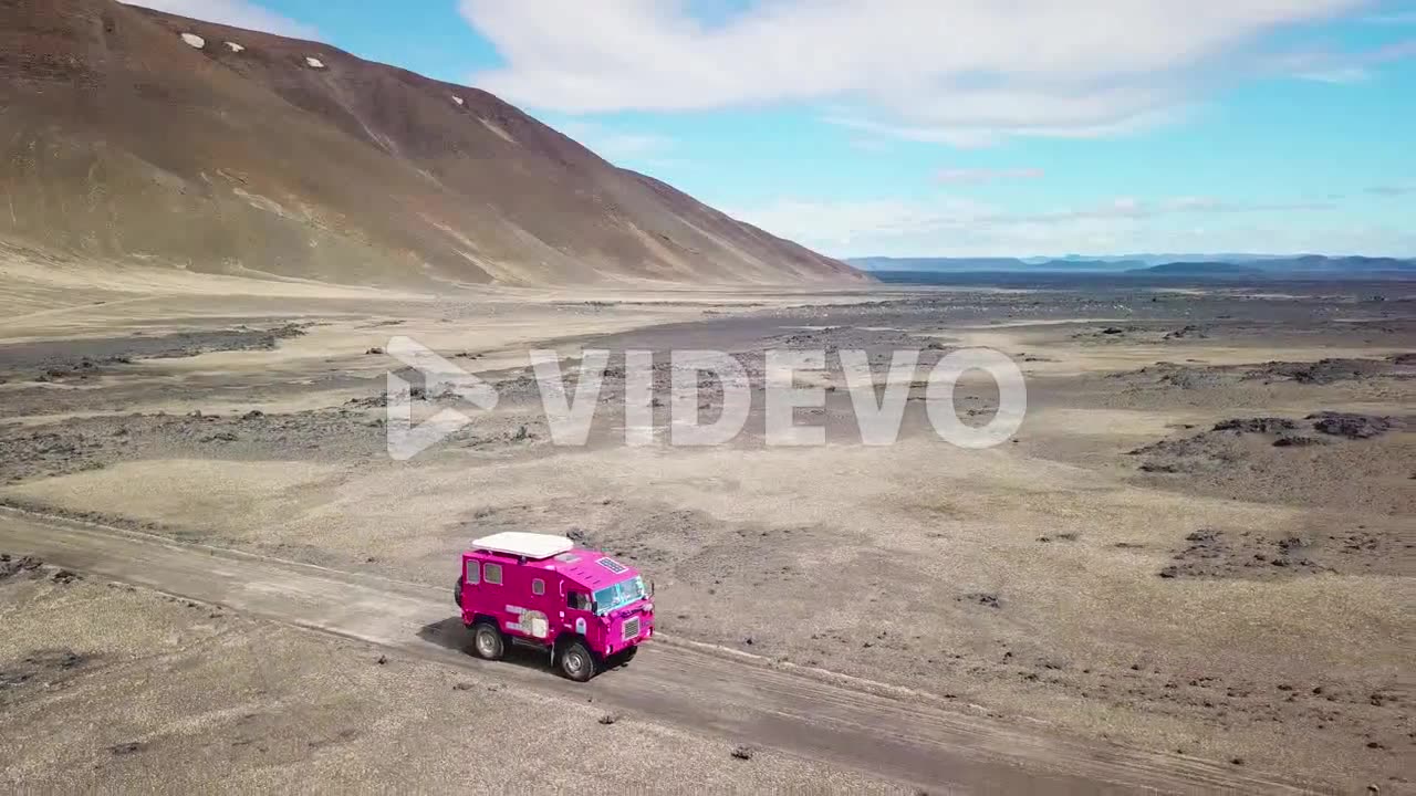 Aerial of a rare pink Land Rover 101 driving through the outback