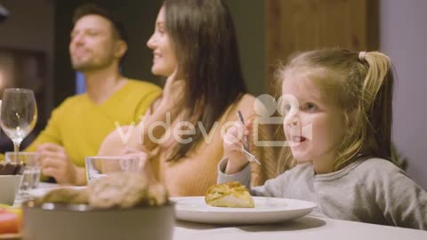 Side View Of Blonde Little Girl Eating Apple Pie Sitting At The Table While Her Parents Talking Duri