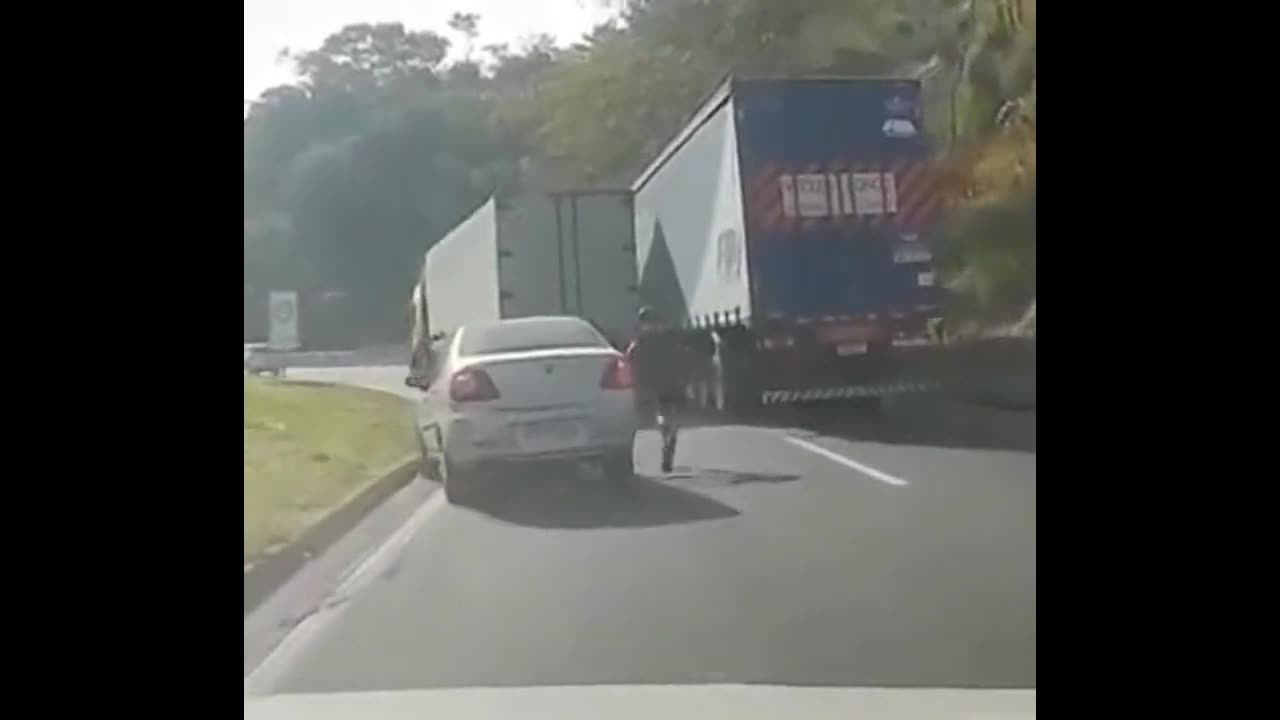 Bicyclist Gets Trapped Between Two Large Truck Trailers, Manages To Squeeze Out Just In Time