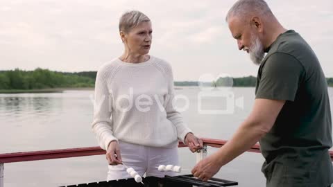 A Couple Of Senior People Roasting Marshmallows Over A Barbecue 1-A couple of senior people roasting