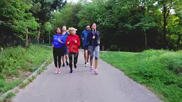 Sportspeople running on road in nature stock video