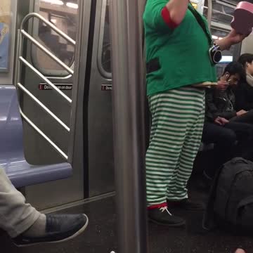 Man in green striped costume quacks on subway train
