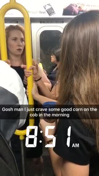 Girl in blue jacket eating corn on the cob on train