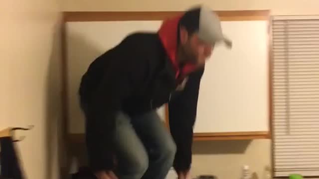 Guy red hoodie jeens boots jumps from kitchen counter onto table and tumbles over