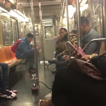 A man smoking a full size hookah on subway train